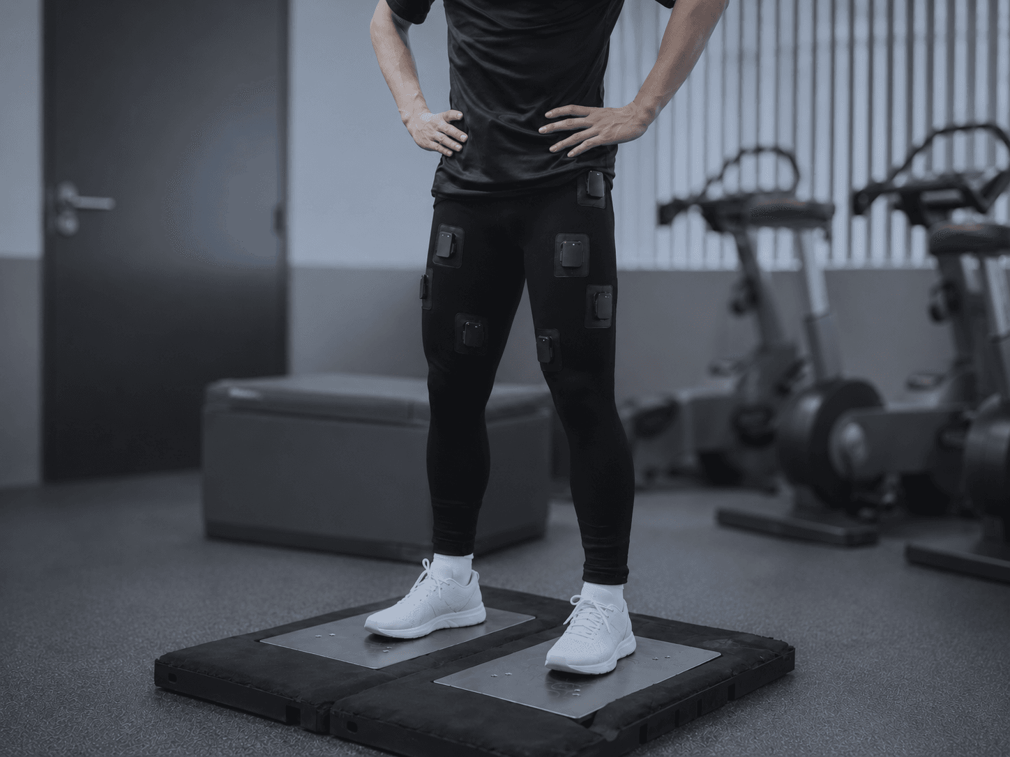 Athlete in the Skinetix leggings performing a jump test on dual force plates, sensor modules visible on the thighs.